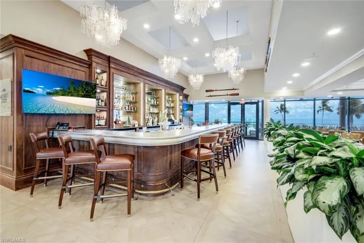 Community bar area featuring open shelves, coffered ceiling, hanging lights, light countertops, and glass fronted cabinets