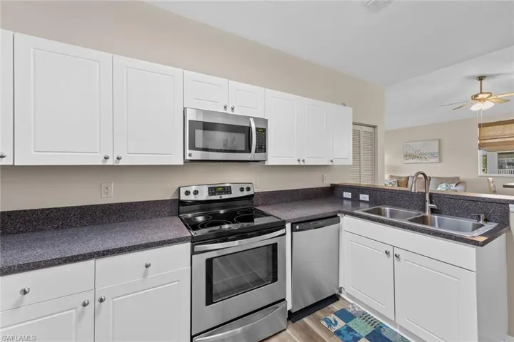 Kitchen featuring appliances with stainless steel finishes, white cabinets, dark countertops, and open floor plan