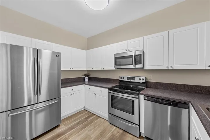Kitchen featuring appliances with stainless steel finishes, white cabinets, and dark countertops
