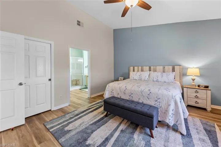 Bedroom with wood finished floors, ensuite bathroom, and a ceiling fan