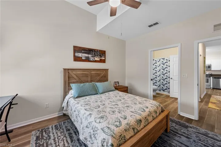 Bedroom featuring dark wood-style flooring, ensuite bath, and ceiling fan