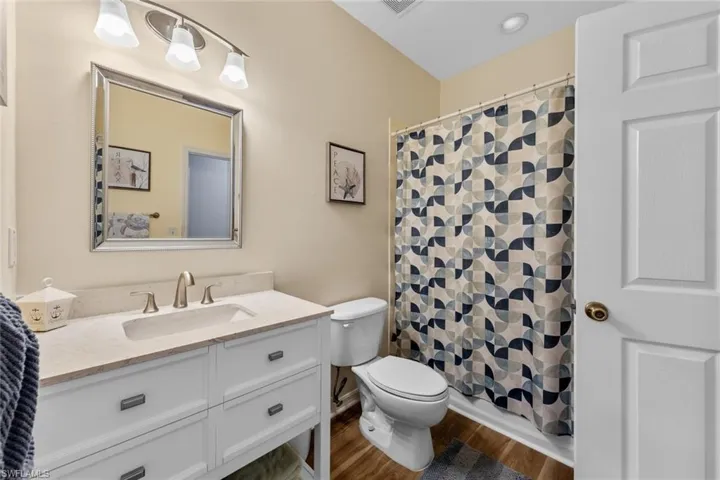 Full bathroom featuring vanity, a shower with shower curtain, and dark wood-style flooring