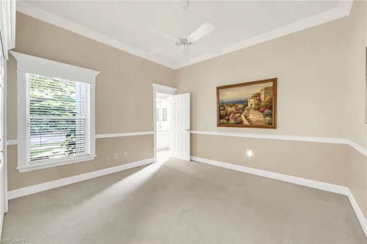 Carpeted spare room with crown molding and a ceiling fan