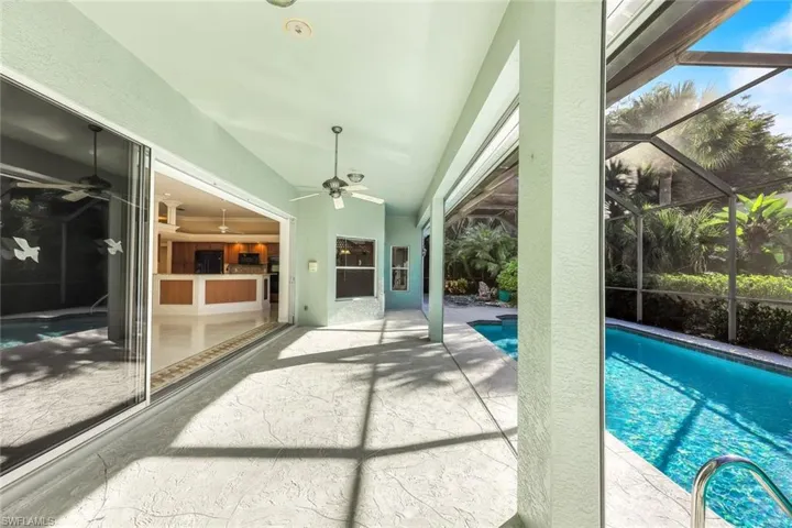 Outdoor pool with a patio, glass enclosure, and a sunroom