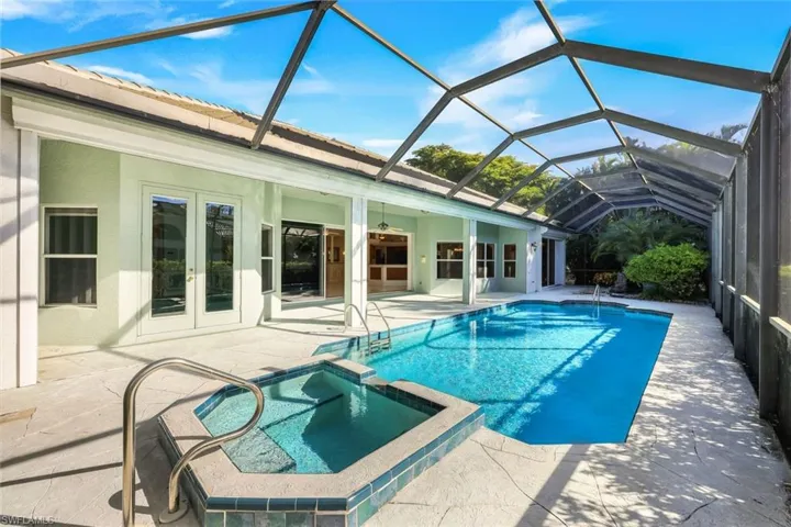 View of swimming pool featuring a sunroom, a pool with connected hot tub, a patio area, french doors, and glass enclosure
