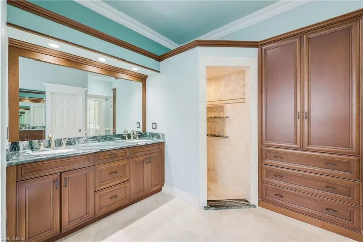 Full bath featuring double vanity, crown molding, and a stall shower