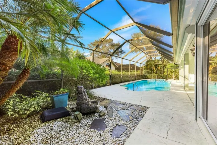 View of swimming pool with a sunroom, a patio area, and glass enclosure