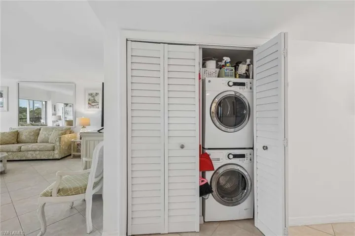 Integrated laundry area with stacked washer and dryer, featuring louvered bi-fold doors