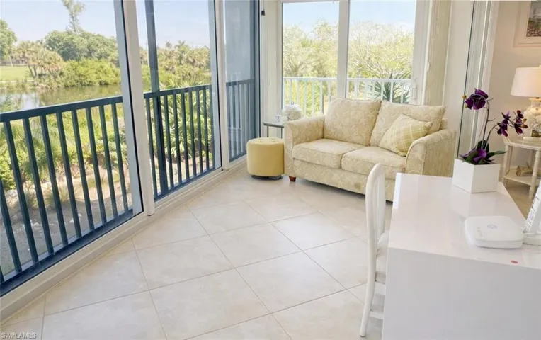 Enclosed balcony featuring tile flooring, floor-to-ceiling glass windows, and metal railings