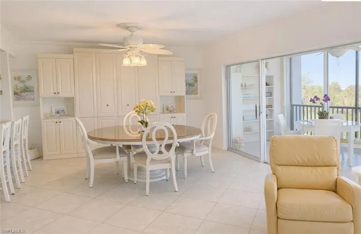 Built-in cabinetry featuring crown molding, large-format tile flooring, multi-light ceiling fan, and expansive sliding glass doors
