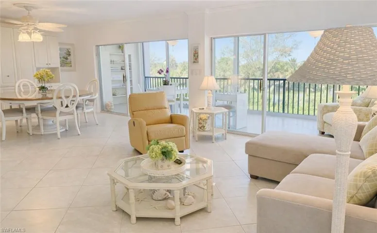 Open-concept floor plan with tile flooring, wall-to-wall sliding glass doors, built-in cabinetry, and a private balcony featuring a metal railing