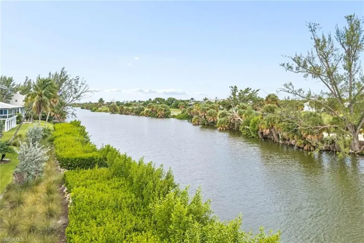 Waterfront property featuring lush landscaping and mature trees