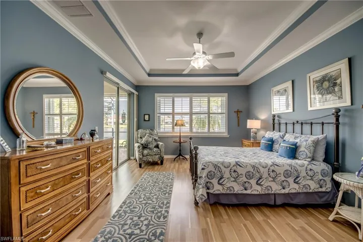 Primary Bedroom W/Tray Ceiling, Crown Molding, Harwood Flooring, A Water View & Lanai Access