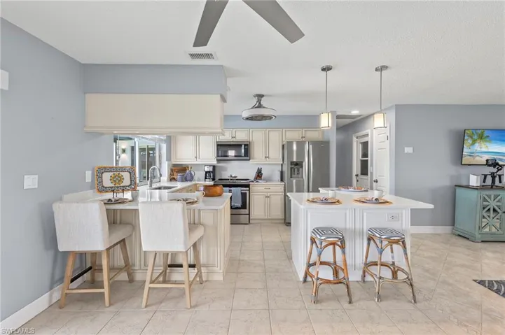 Kitchen with appliances with stainless steel finishes, light tile patterned flooring, cream cabinets, and a kitchen bar