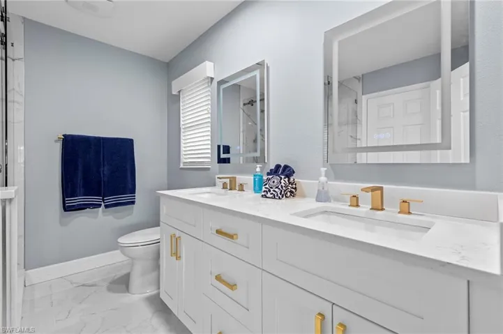 Bathroom featuring tile patterned floors, an enclosed shower, vanity, and toilet