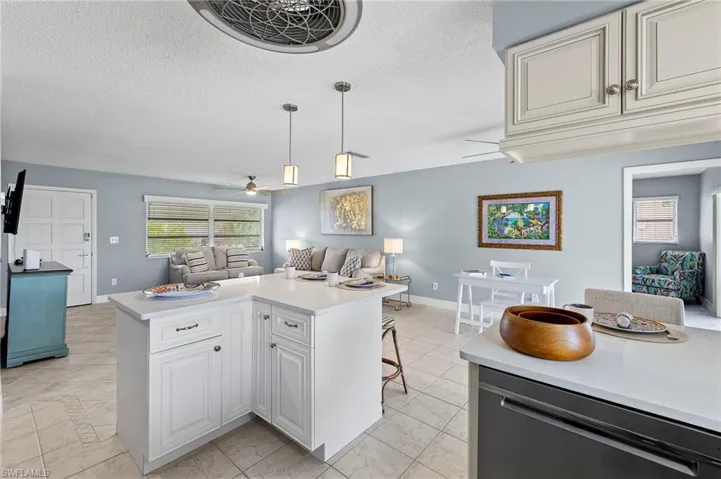 Kitchen with a textured ceiling, ceiling fan, light tile patterned flooring, and hanging light fixtures
