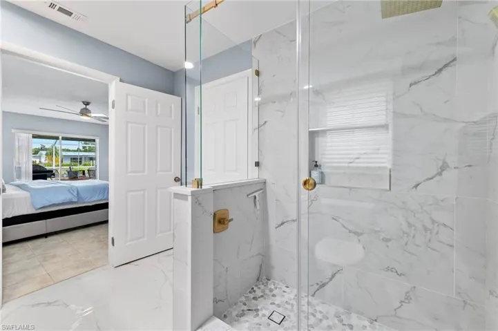 Bathroom featuring ceiling fan, tiled shower, and tile patterned floors