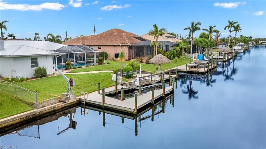 View of dock featuring a water view, a lawn, and a lanai