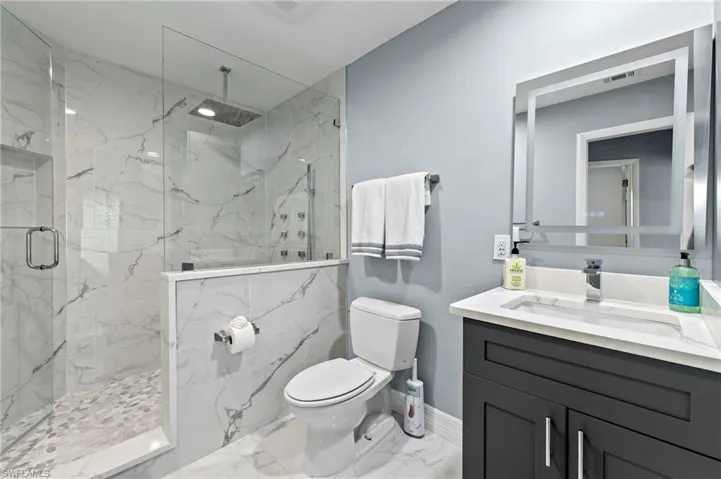 Bathroom with tile patterned flooring, an enclosed shower, vanity, and toilet