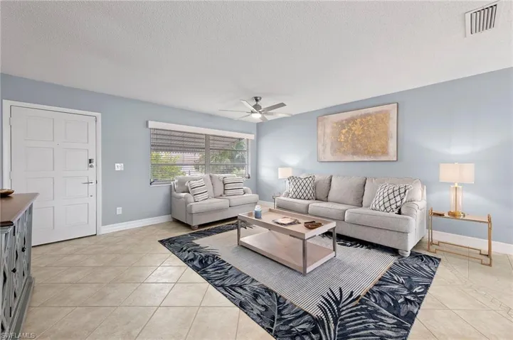 Tiled living room featuring ceiling fan and a textured ceiling