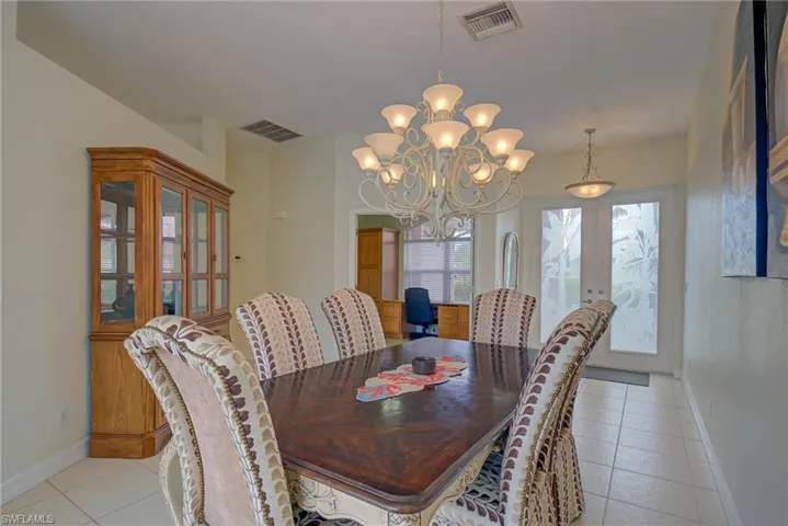 Dining area with light tile patterned floors, french doors, and a chandelier