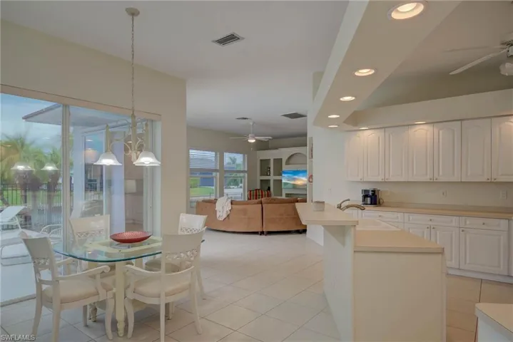 Kitchen with a ceiling fan, recessed lighting, light countertops, open floor plan, and white cabinets