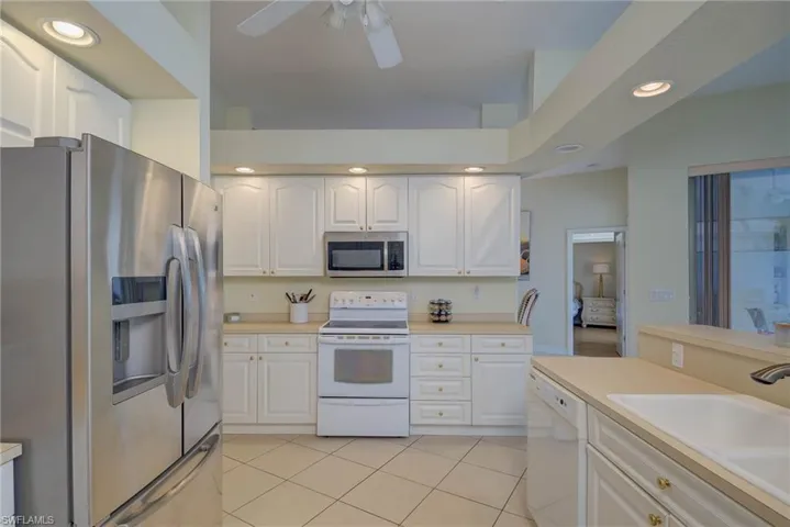 Kitchen with recessed lighting, stainless steel appliances, light countertops, light tile patterned flooring, and white cabinetry