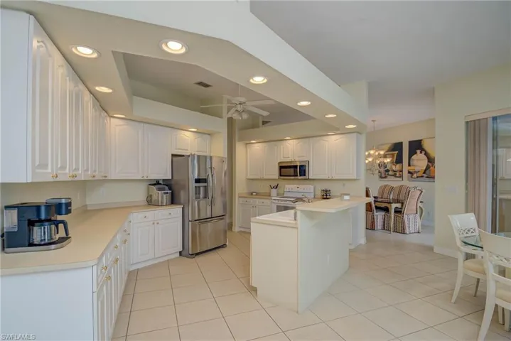 Kitchen featuring recessed lighting, appliances with stainless steel finishes, white cabinets, light tile patterned flooring, and light countertops