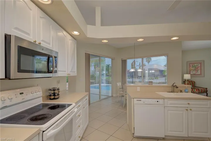 Kitchen with white appliances, white cabinetry, recessed lighting, light tile patterned floors, and light countertops
