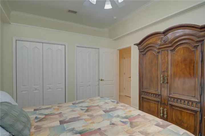 Bedroom featuring two closets, ceiling fan, and crown molding