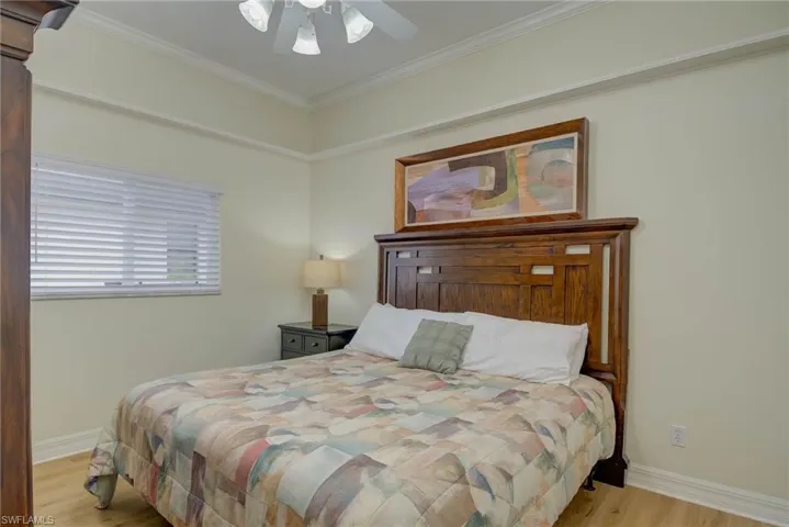 Bedroom featuring light wood finished floors, ornamental molding, and ceiling fan