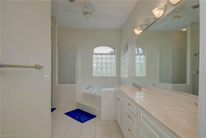 Full bath featuring a ceiling fan, a garden tub, double vanity, and a walk in shower