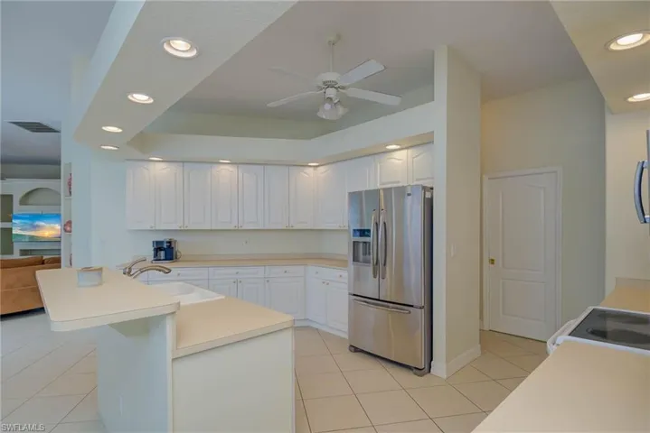 Kitchen with recessed lighting, stainless steel appliances, light countertops, light tile patterned flooring, and white cabinetry