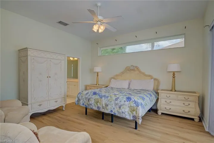 Bedroom featuring connected bathroom, wood finished floors, and a ceiling fan