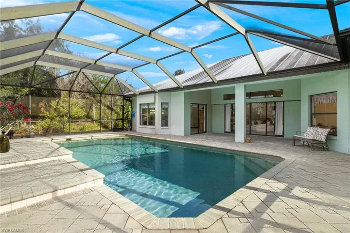 View of swimming pool featuring a patio area and glass enclosure