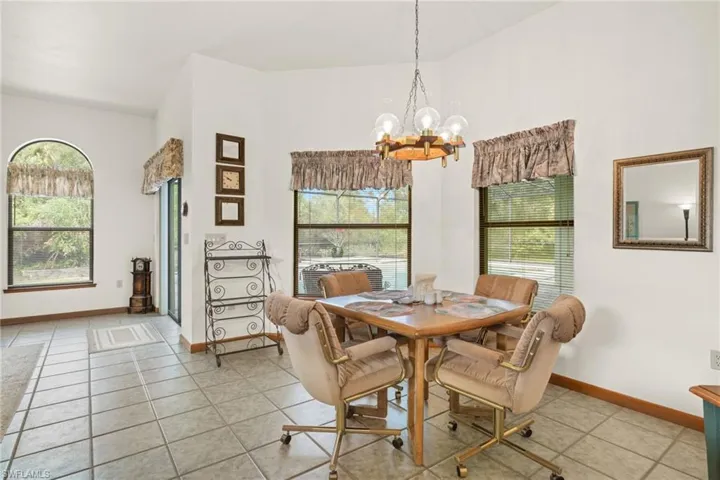 Dining area featuring high vaulted ceiling, a healthy amount of sunlight, light tile patterned flooring, and an inviting chandelier
