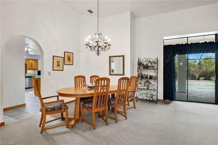 Dining room featuring a high ceiling, light colored carpet, and ceiling fan with notable chandelier