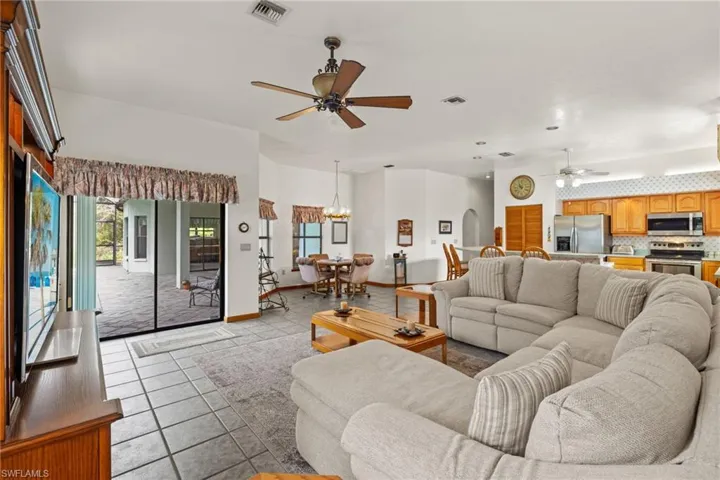 Living room featuring ceiling fan with notable chandelier and light tile patterned floors