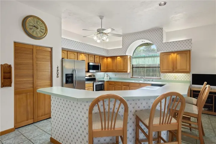 Kitchen with kitchen peninsula, ceiling fan, appliances with stainless steel finishes, light tile patterned floors, and sink