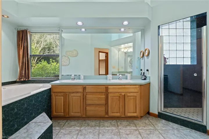 Bathroom with vanity, plus walk in shower, a healthy amount of sunlight, and tile patterned floors