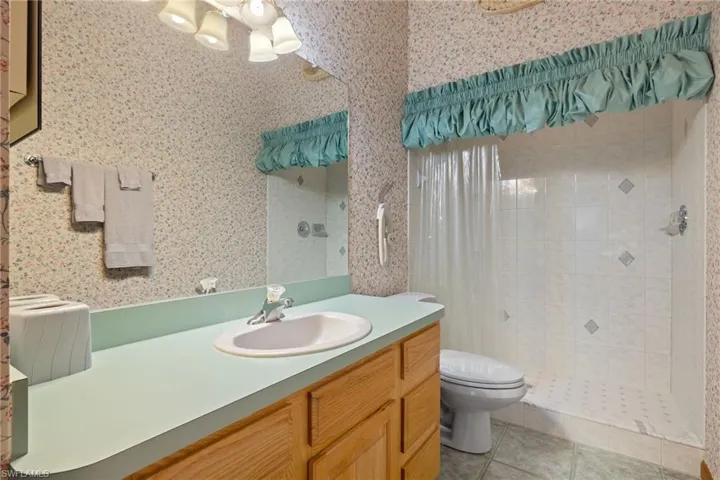 Bathroom featuring toilet, vanity, tile patterned floors, and a shower with shower curtain