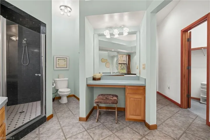Bathroom featuring vanity, toilet, tiled shower, and tile patterned floors