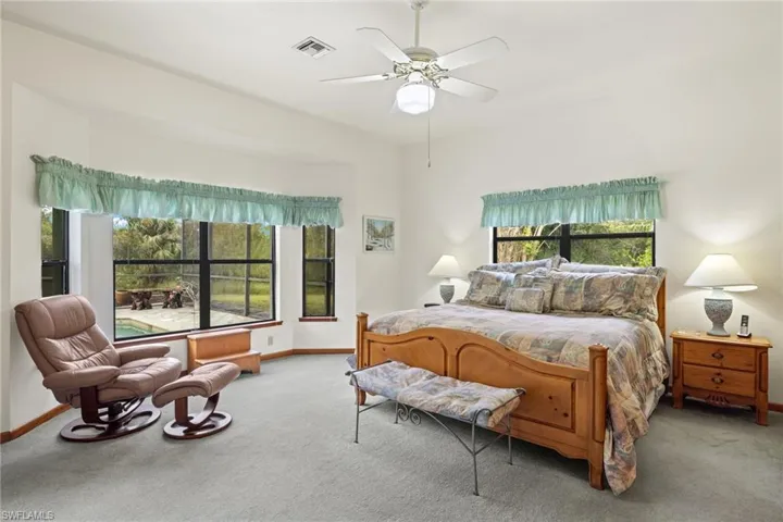 Bedroom featuring light carpet and multiple windows