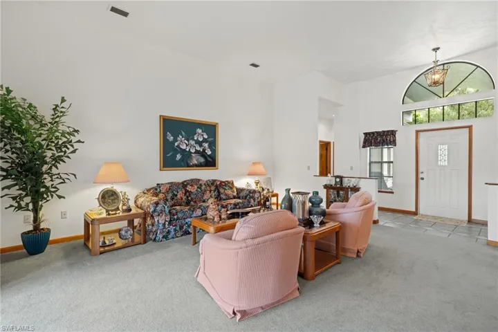 Carpeted living room featuring a towering ceiling and an inviting chandelier