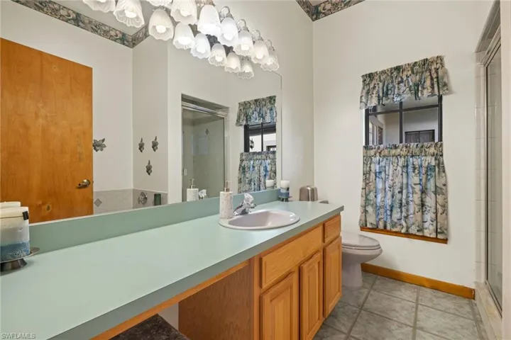 Bathroom with toilet, tile patterned flooring, vanity, and a shower with door