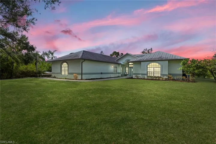 Back house at dusk featuring a yard