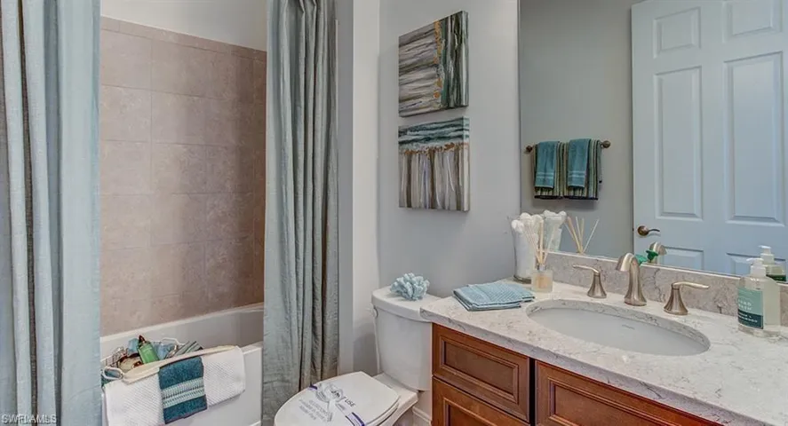 Full bathroom with shower / bath combo with shower curtain, vanity, and toilet