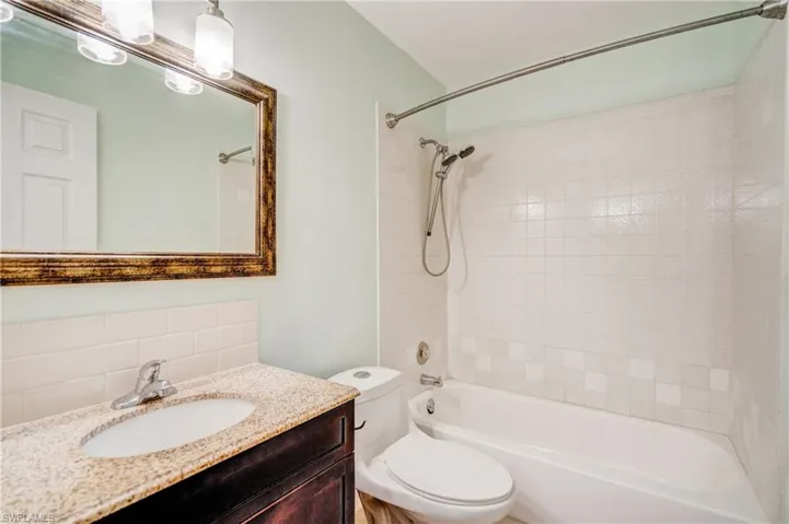 Full bathroom with vanity, toilet, tiled shower / bath, and tasteful backsplash