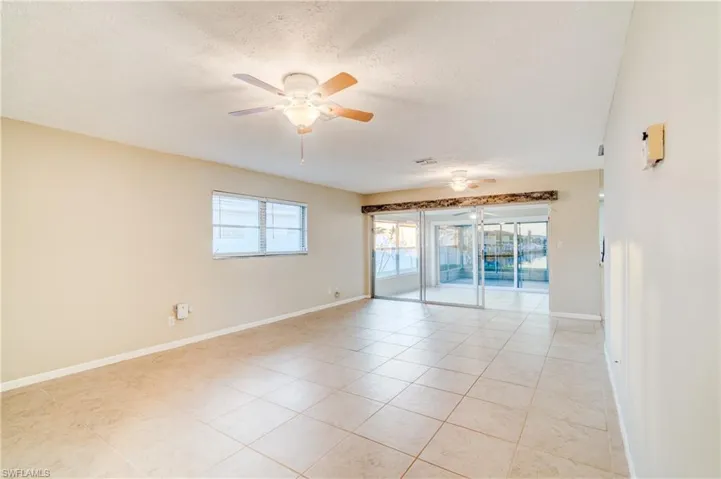 Tiled empty room with ceiling fan and a textured ceiling