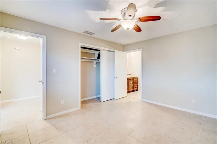 Unfurnished bedroom featuring a closet, ceiling fan, light tile patterned floors, and a textured ceiling